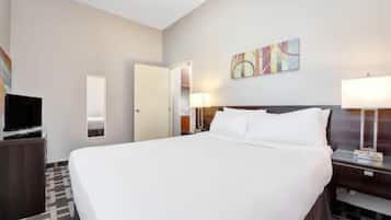 Habitación de hotel con una cama grande, televisión, escritorio con lámpara y un cuadro en la pared.