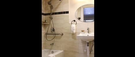 Un bagno moderno con una vasca, una doccia con soffione manuale, un lavandino e uno specchio.