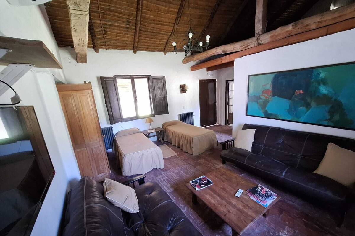 Una habitación acogedora con techo de madera, una pantalla de televisión grande, dos camas, un sofá y una mesa de centro.