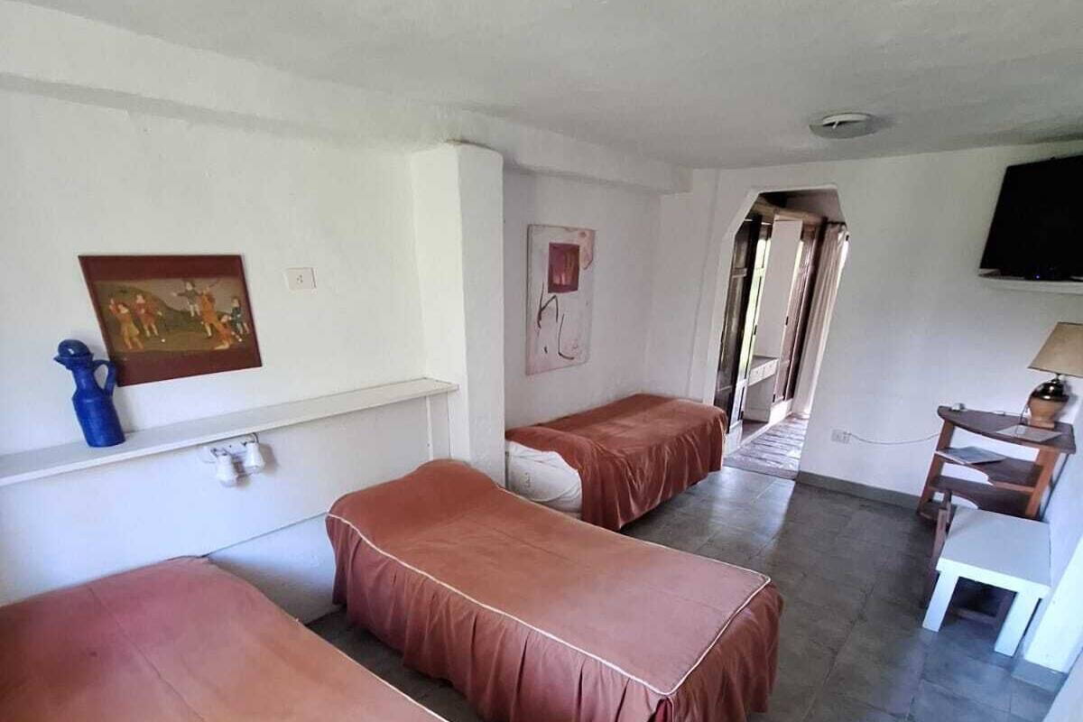 Un dormitorio con tres camas individuales, un escritorio, una silla y un televisor.