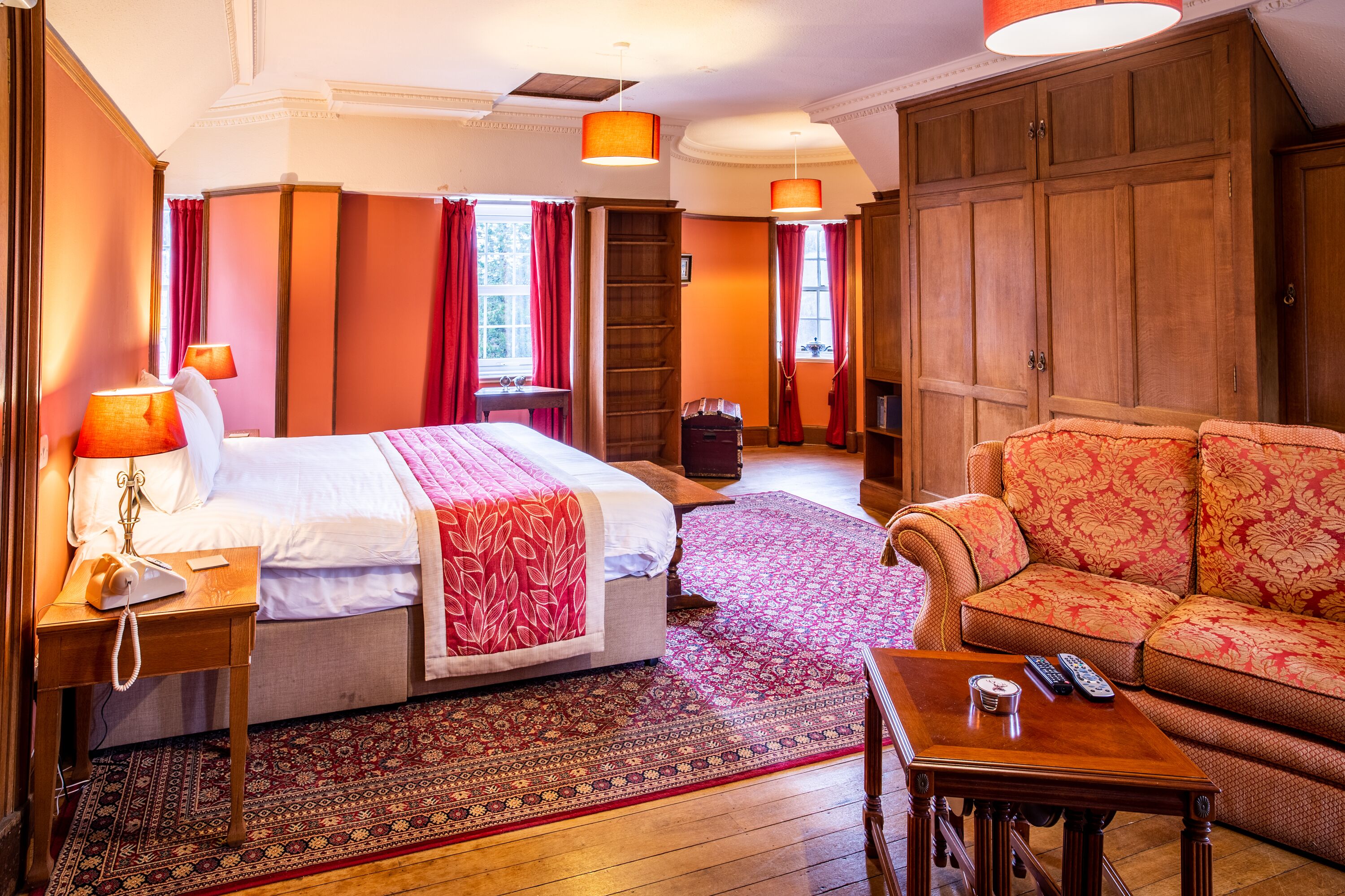 Une chambre d’hôtel comprenant un lit, un canapé, une petite table, une table de chevet et une armoire.