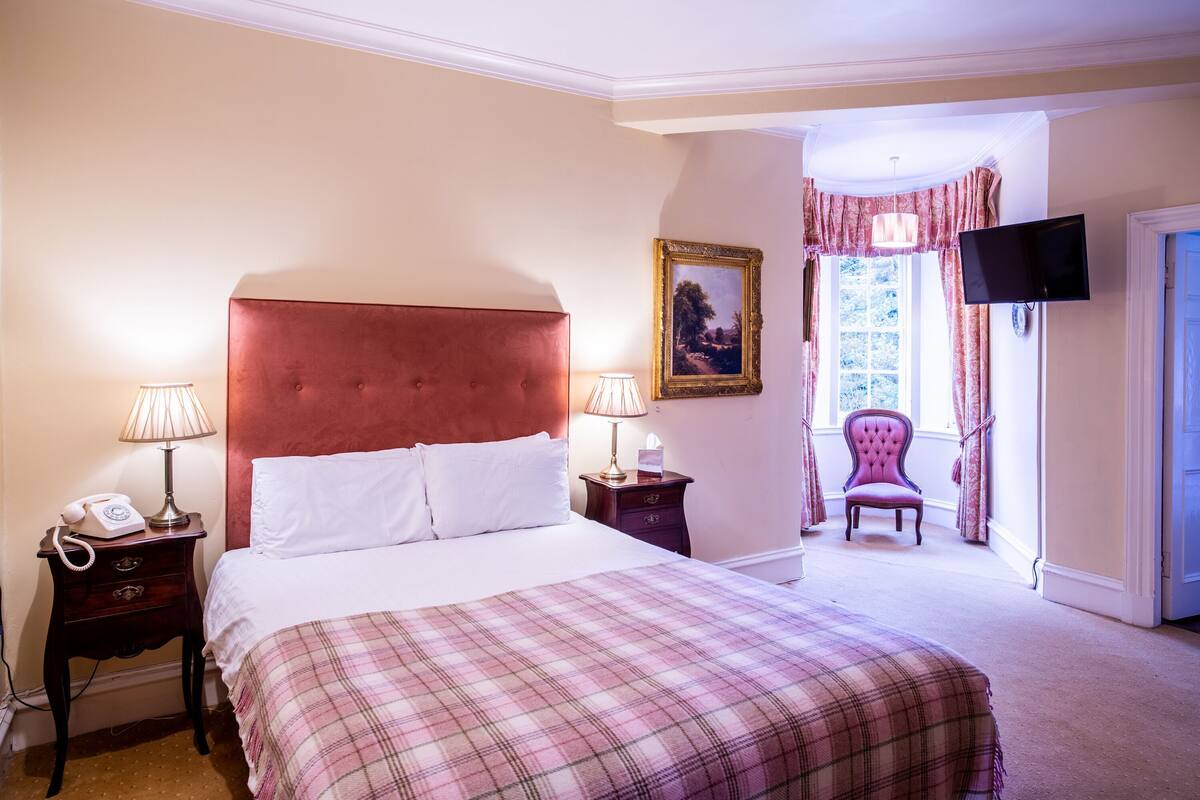 Une chambre à coucher comprenant un lit, des lampes de chevet, un téléphone, une chaise et un téléviseur.