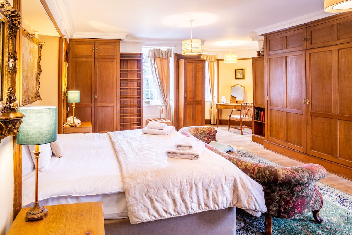 Une chambre d’hôtel avec un grand lit, une armoire en bois, un bureau et une chaise.
