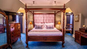 A four-poster bed with a patterned canopy, wooden nightstands with lamps, a dresser, and a mirror.