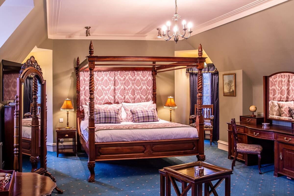 Un lit à baldaquin, une commode, un miroir et un bureau avec une chaise.