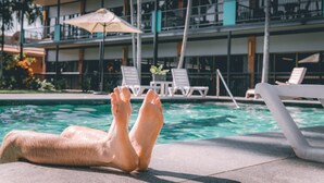 A poolside area with lounge chairs and an umbrella. - Litchfield Outback Resort (Batchelor)