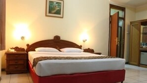 Uma cama de solteiro com cabeceira de madeira, duas luminárias de cabeceira, uma mesinha de cabeceira e um quadro na parede.