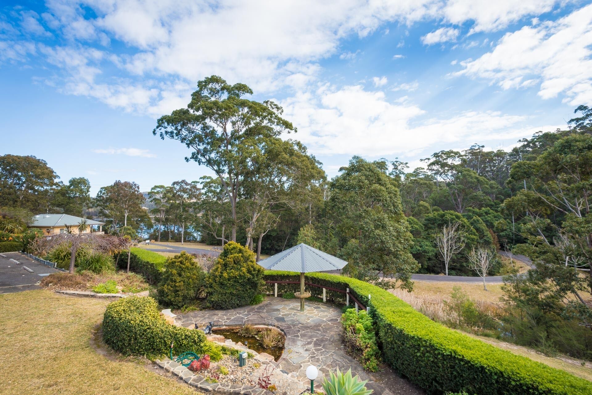 A residential area with a well-maintained garden, a gazebo, and a large tree.