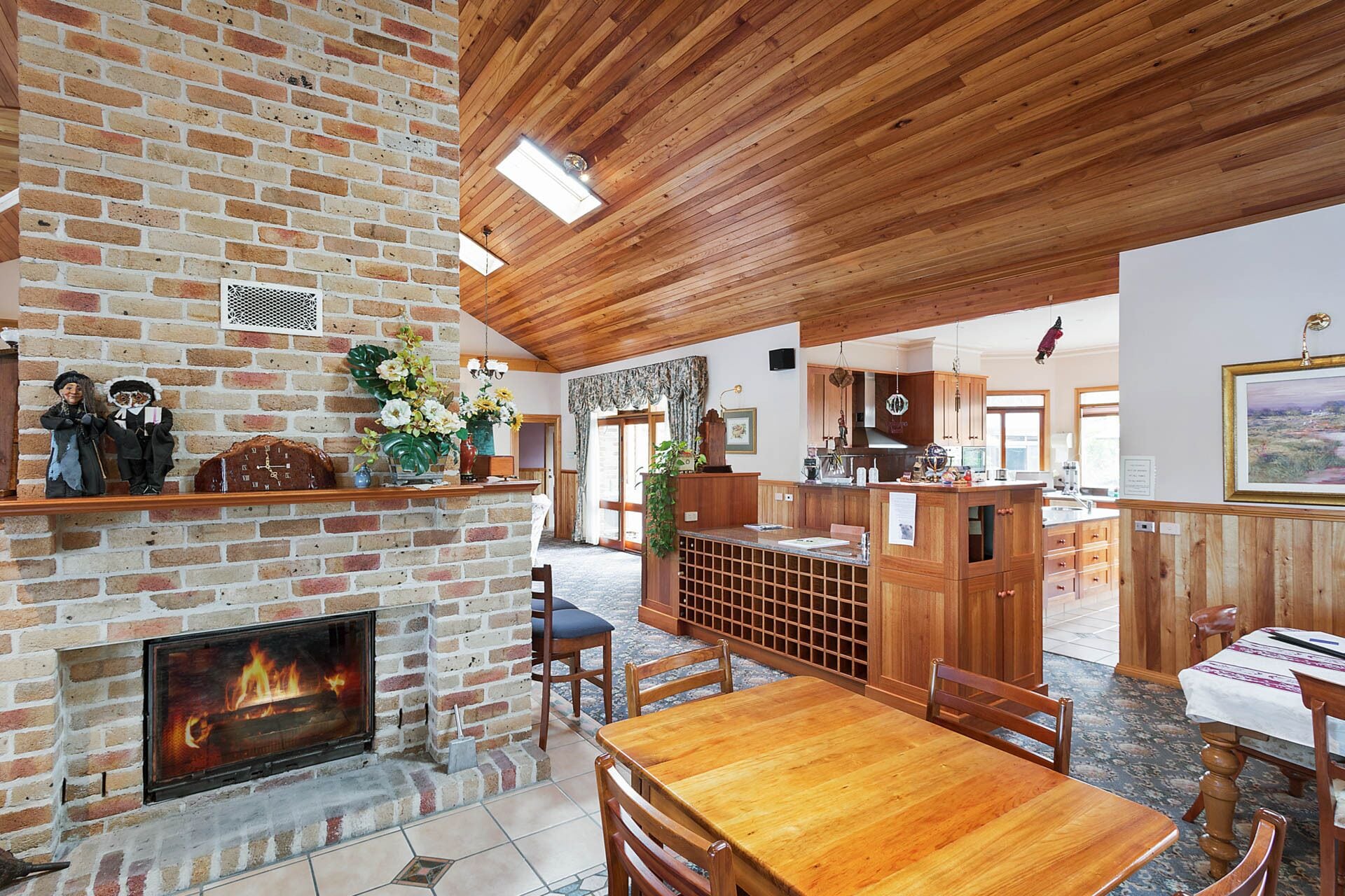 A spacious interior with a brick fireplace, wooden ceiling, and a dining area with a wooden table and chairs.