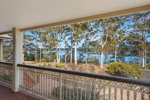 A balcony with a view of a lake and trees. - Robyns Nest Boutique Resort (Merimbula)