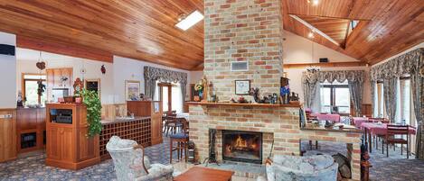 A spacious room with a brick fireplace, wooden ceiling, and patterned carpet.