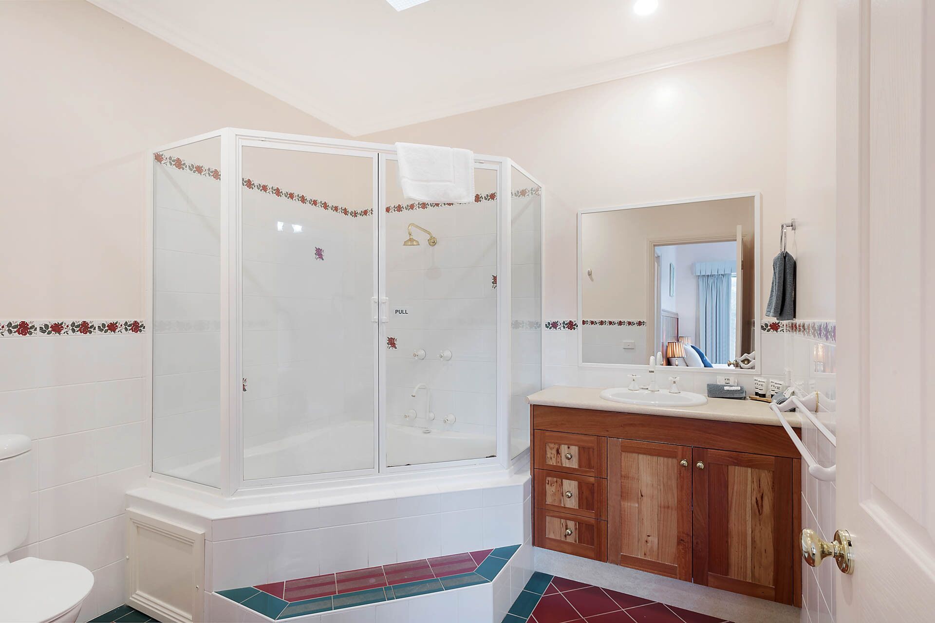 A bathroom with a glass-enclosed shower, a sink with a wooden vanity, and a mirror above the sink.