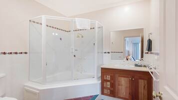 A bathroom with a glass-enclosed shower, a sink with a wooden vanity, and a mirror above the sink.
