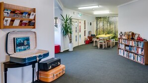 Eine Bibliothek mit Bücherregalen, einem Tisch mit Stühlen und einem Klavier.