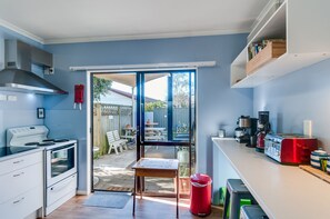 A compact kitchen with a stove, oven, and a dining area visible through a glass door.