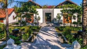 A modern building with a central entrance, surrounded by lush greenery and palm trees. - Jeeva Saba Bali (Gianyar)