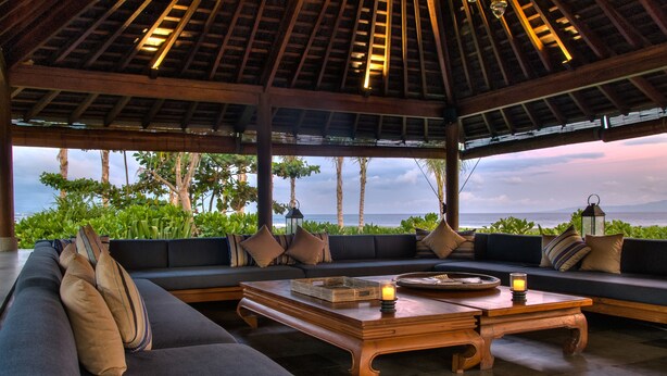 A spacious seating area with a view of the ocean, featuring a wooden coffee table and a sofa with cushions. - Jeeva Saba Bali (Gianyar)