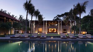 A modern resort with a pool, lounge chairs, and palm trees. - Jeeva Saba Bali (Gianyar)