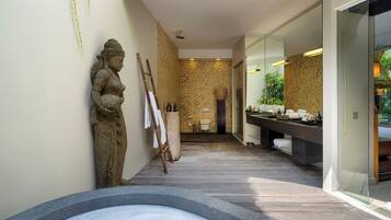 Relax in a spacious bathroom with a bathtub, stone statue, and ample storage.