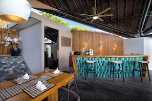 A modern bar area with a wooden ceiling, a bar counter, and two stools. - Villa Toraja by Lifestyle Retreats (Canggu)
