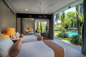 A modern hotel room with two beds, a ceiling fan, and a large sliding glass door leading to a pool area. - Villa Toraja by Lifestyle Retreats (Canggu)