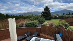 A hot tub on a wooden deck with lounge chairs and a view of mountains. - Vibrant Living Retreat (Hanmer Springs)