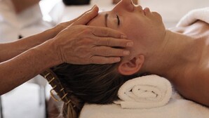 A person receiving a facial treatment in a room with a white towel and a black chair. - Vibrant Living Retreat (Hanmer Springs)