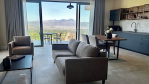 A modern living room with a sofa, chairs, a dining table, and a kitchen area. - Cape Vermeer (Cape Town)
