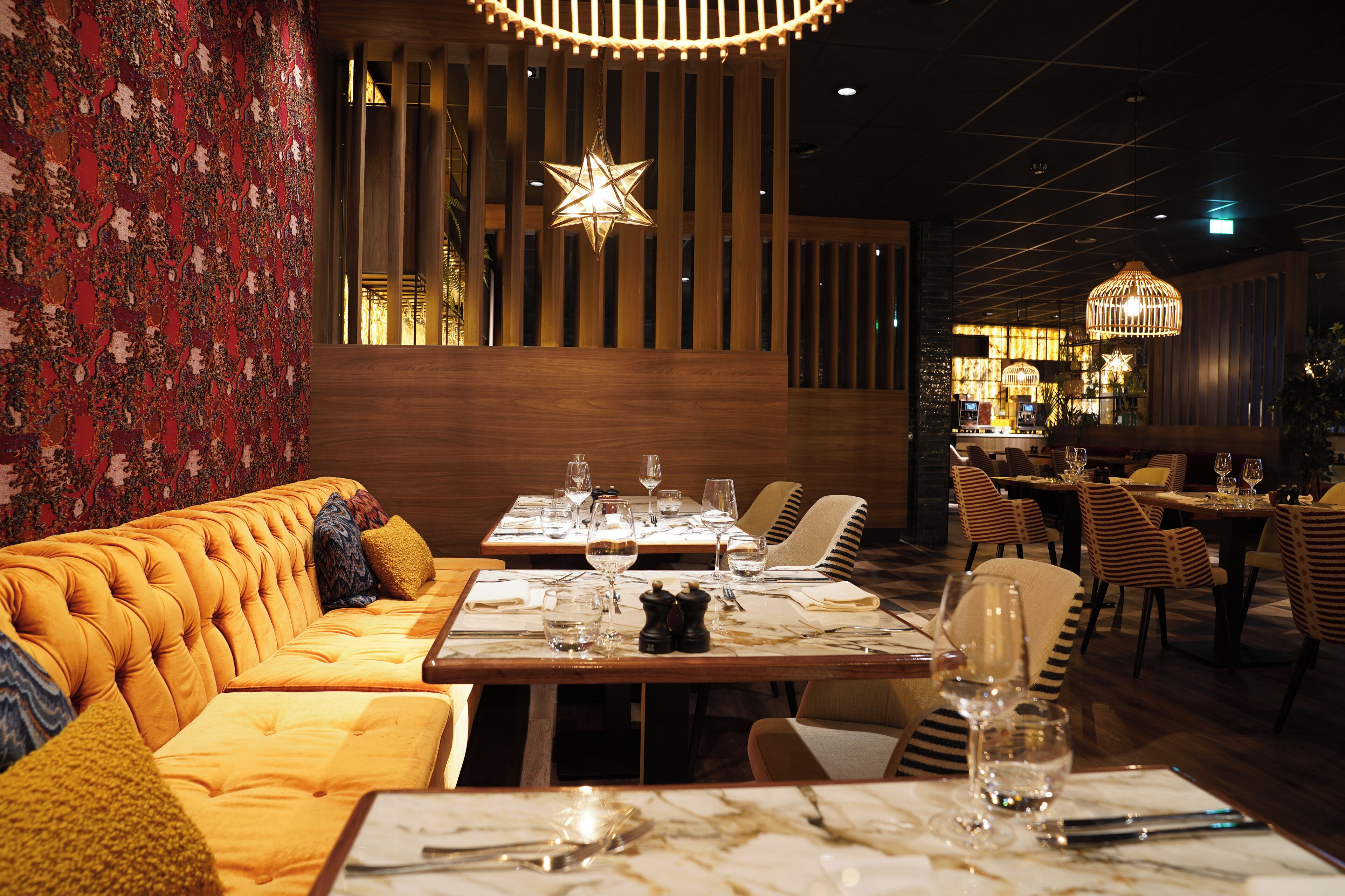 Een restaurant met houten vloer, een bank, tafels en stoelen.