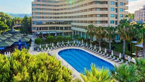 A hotel with a large pool, multiple floors, and a surrounding garden with palm trees. - Özkaymak Select Hotel - Ultra All Inclusive  (Alanya)