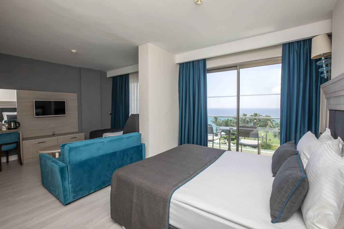 Ein modernes Hotelzimmer mit einem großen Bett, einem Schreibtisch, einem Sofa und einem Fernseher.