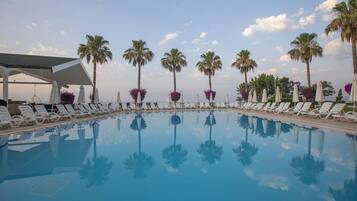 A swimming pool with lounge chairs and palm trees.