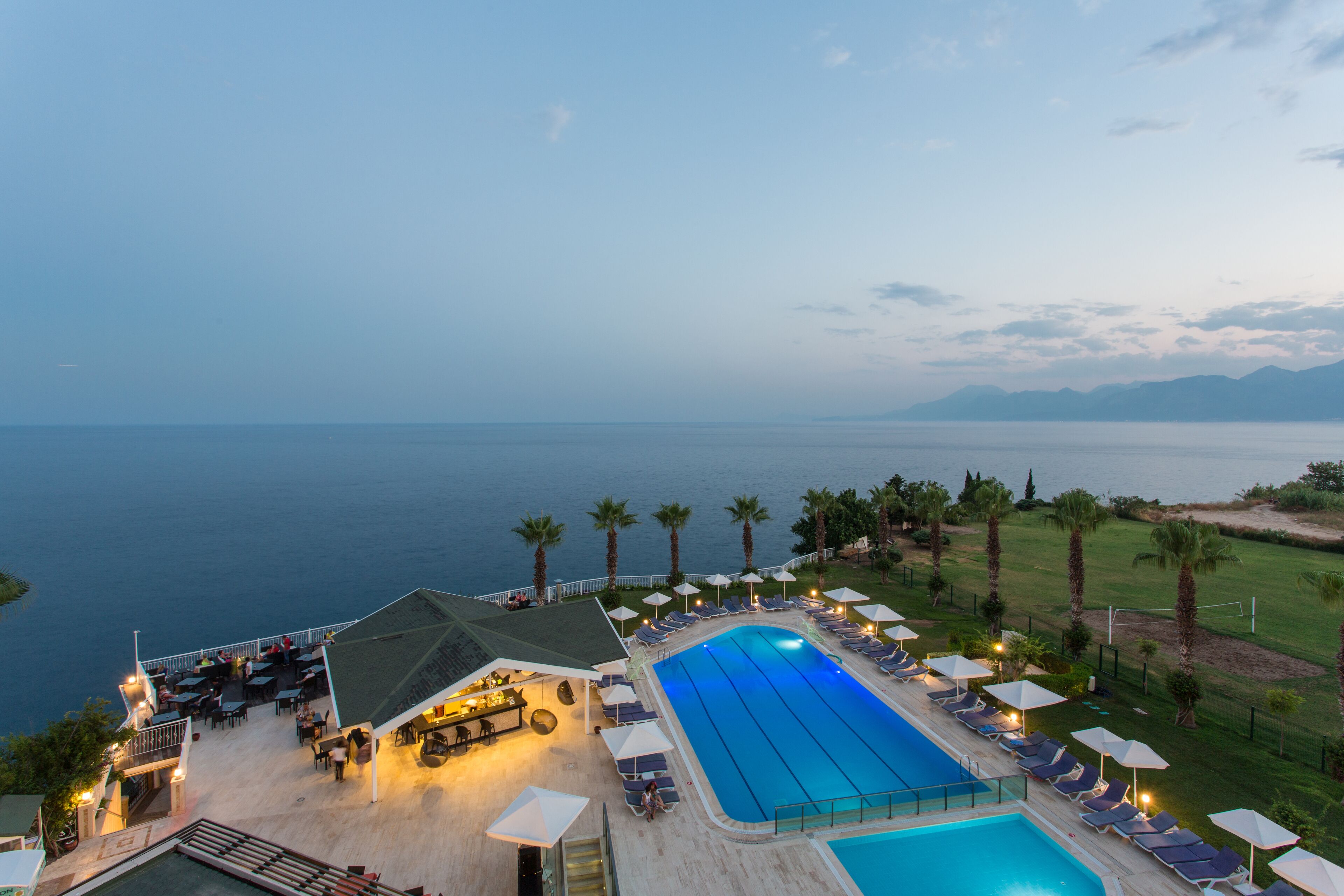 Un resort con una amplia piscina, mobiliario exterior y vistas al mar.