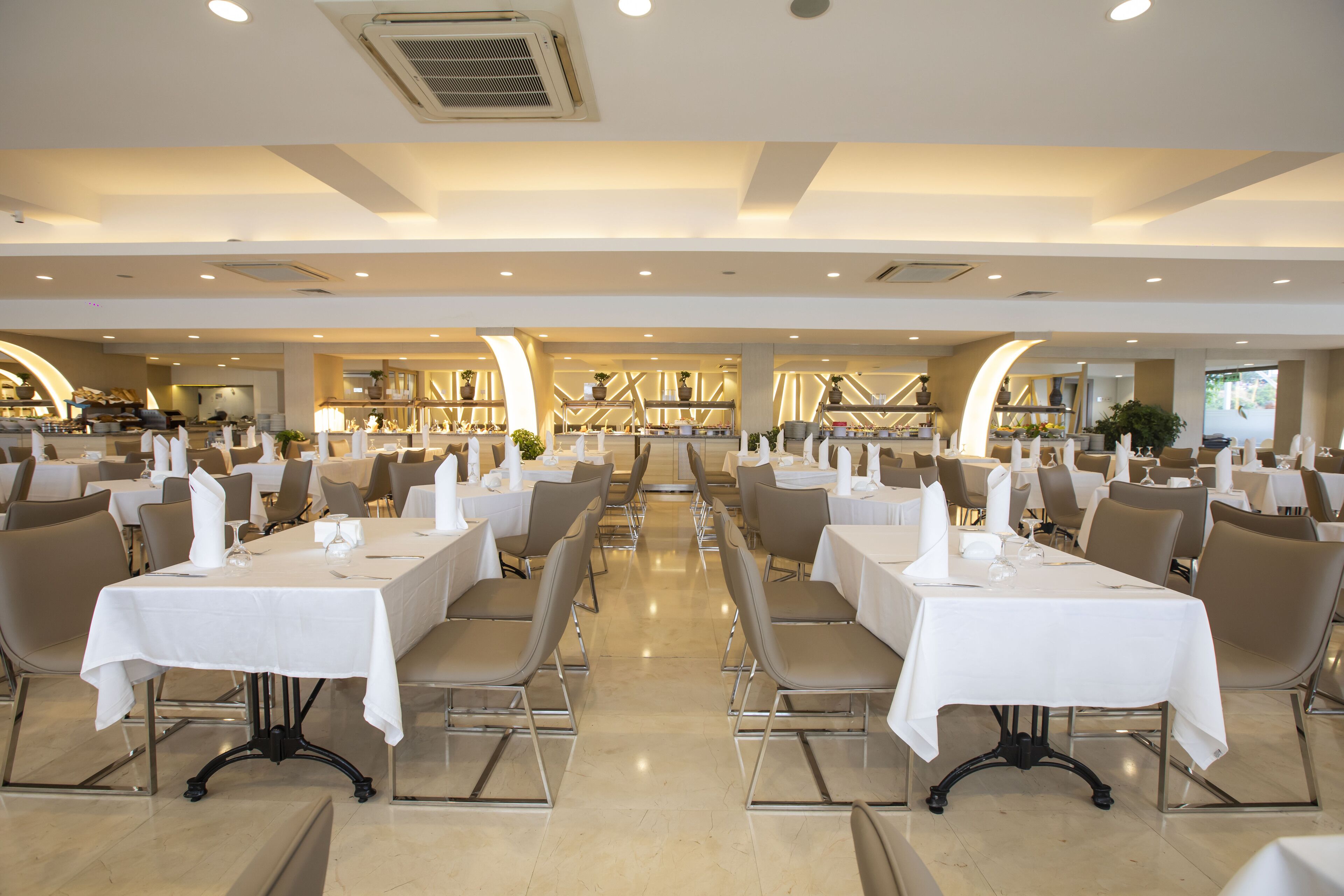 A spacious restaurant with multiple tables and chairs, arranged in a symmetrical layout.