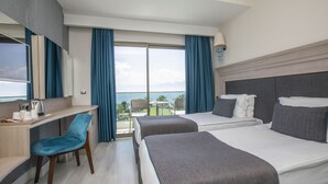 A hotel room with two beds, a desk, a chair, and a large window with curtains. - Falcon Hotel (Antalya)