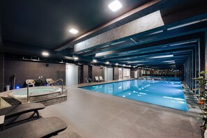 Hồ bơi trong nhà, ghế dài tắm nắng, nhân viên cứu hộ trong khuôn viên 