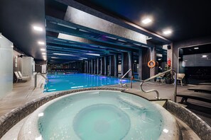 An indoor swimming pool with a hot tub, lounge chairs, and a modern architectural design. - Bliss Residence & Spa (Budapest)