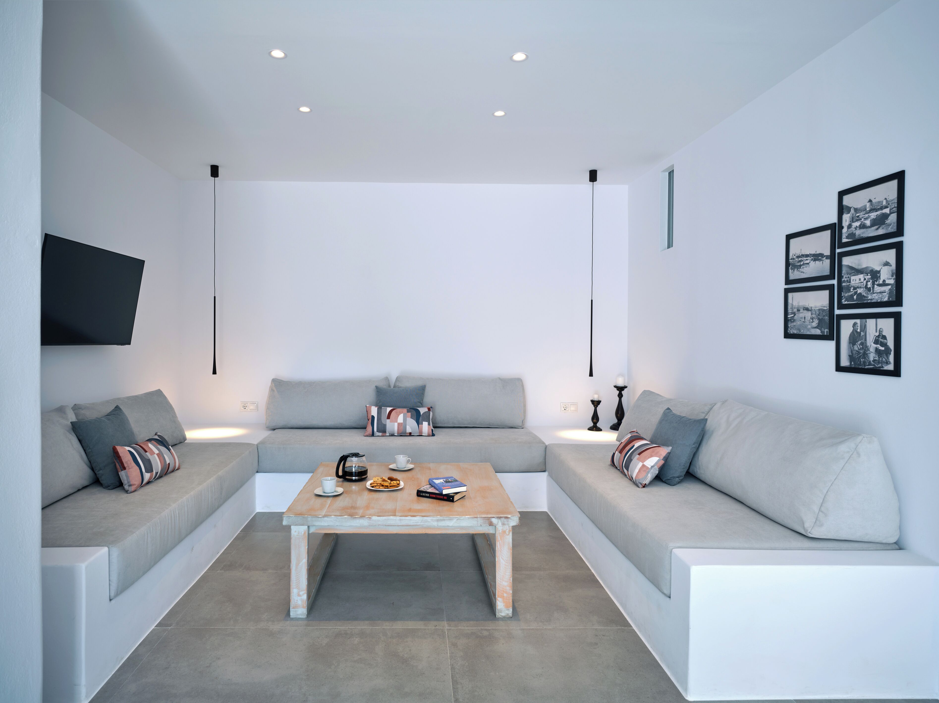 A modern living room with a sofa set, a coffee table, and a flat-screen TV mounted on the wall.