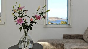 A room with a view of the sea, a sofa, and a vase with flowers on a table. - Blue Mare Villas (Paros)