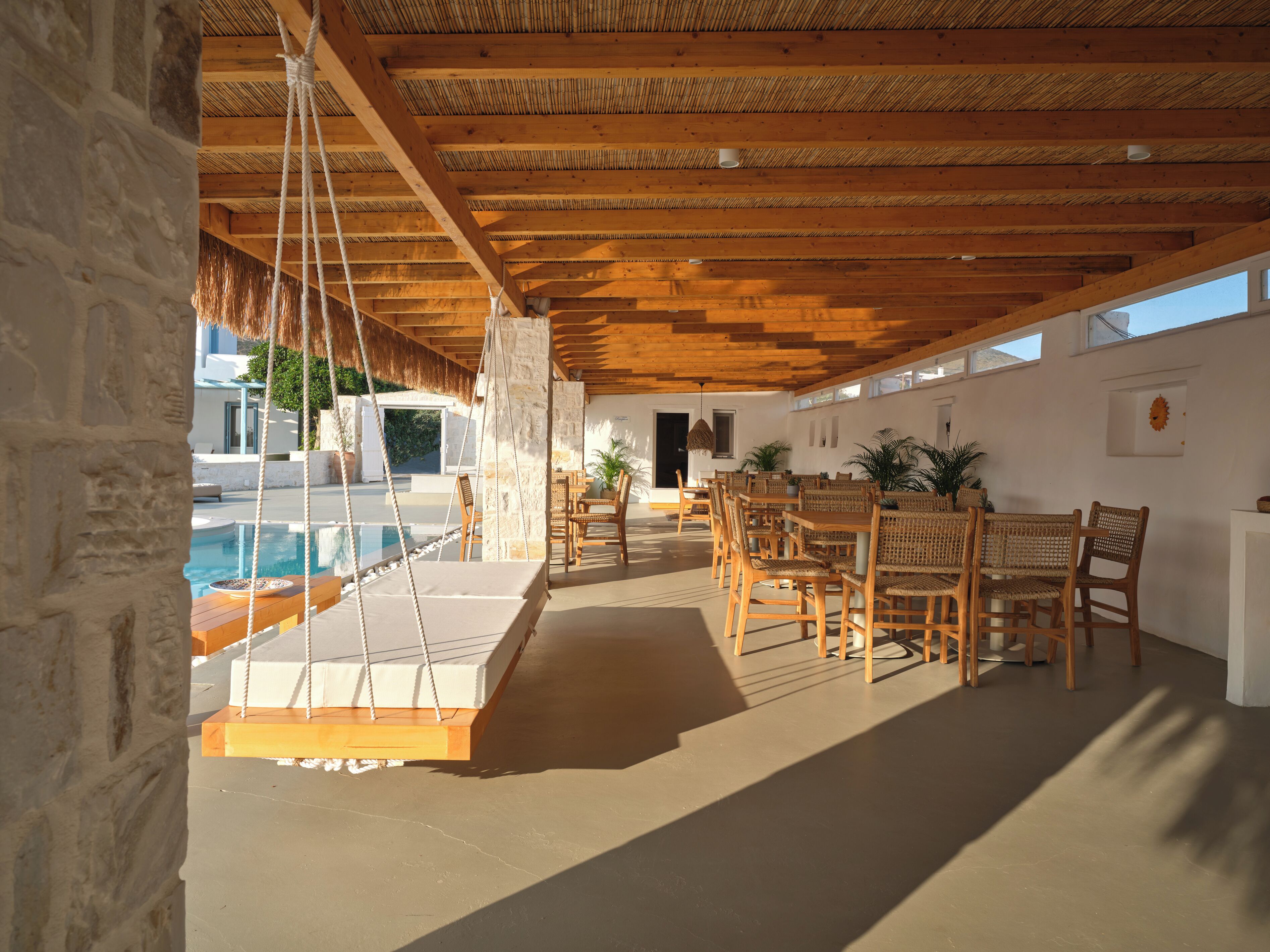 Un espacio al aire libre cubierto con piscina, muebles de madera y paredes de piedra.