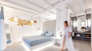 Un dormitorio moderno con cama, mesita de noche y baño con lavamanos y espejo.