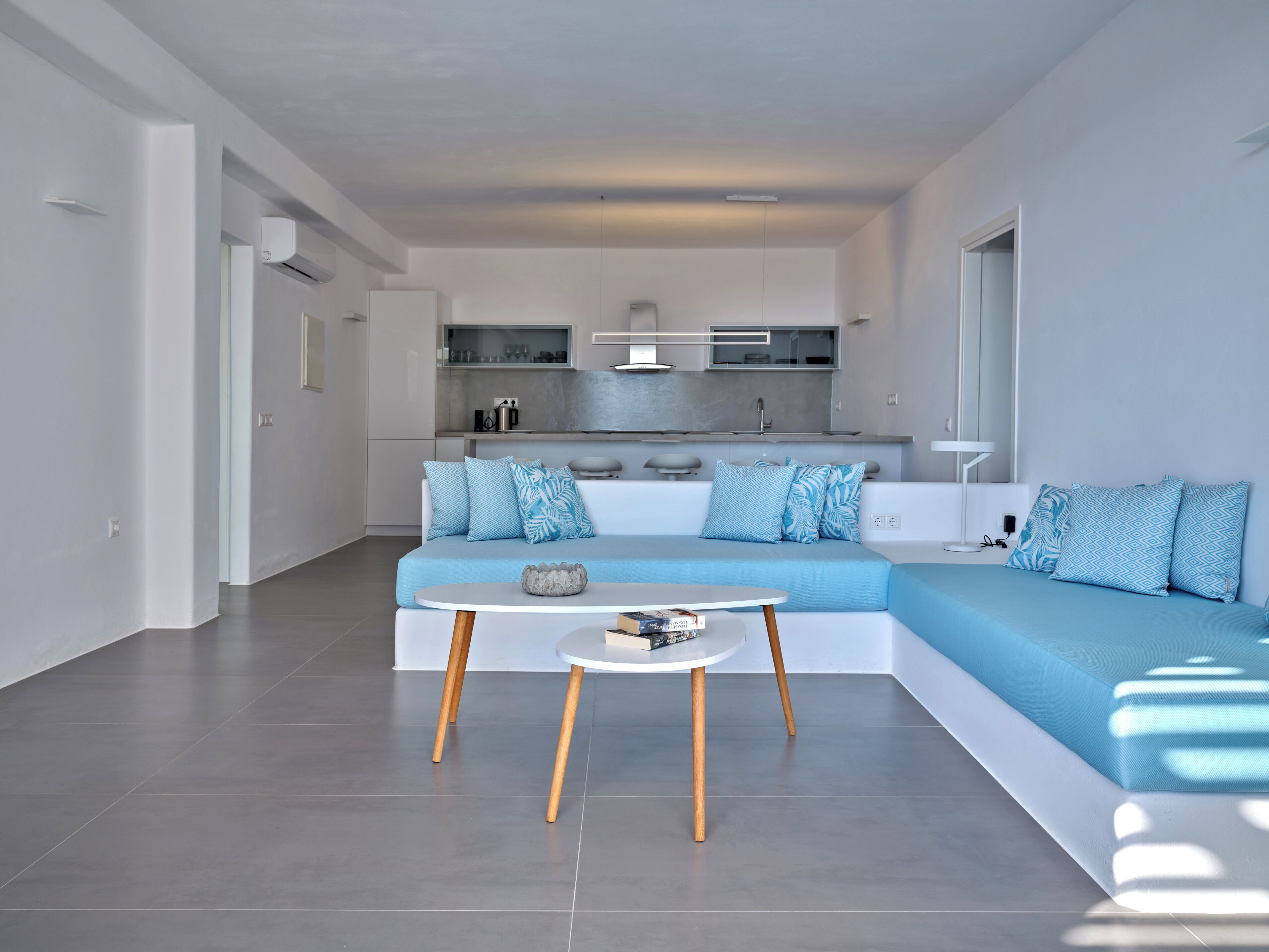 Una sala de estar moderna con un sofá seccional, una mesita redonda y una cocina al fondo.