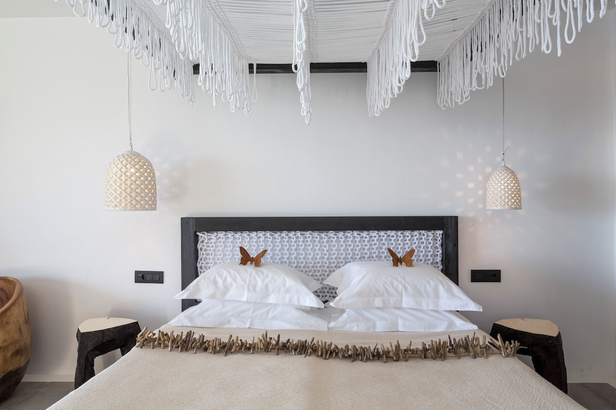 Un dormitorio moderno con una cama grande, dos lámparas colgantes y un cabecero de madera.