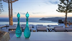 A seaside terrace with lounge chairs and two decorative vases.