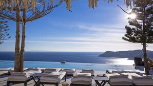 A poolside area with lounge chairs and a view of the sea.