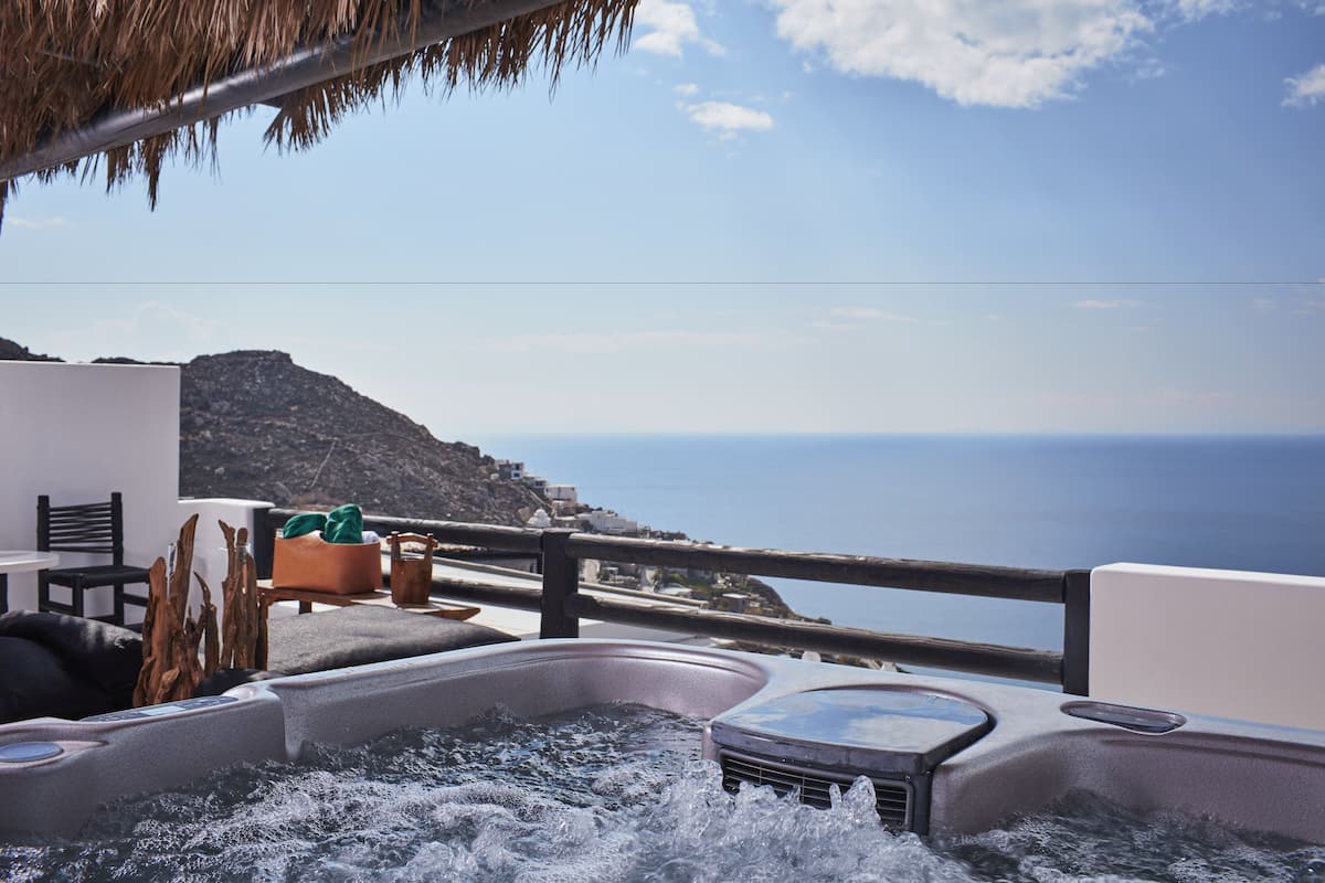 A hot tub area with a view of the sea and a mountainous landscape.