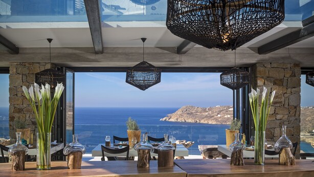 A dining table with glass vases and a view of the sea.