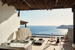 Un balcón con bañera de hidromasaje, sillones de descanso y vista al mar.