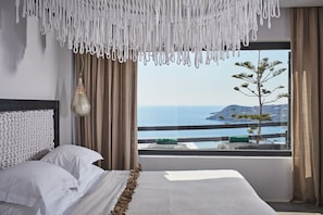 Relax in this serene room with a large bed, a unique light fixture, and a stunning sea view.