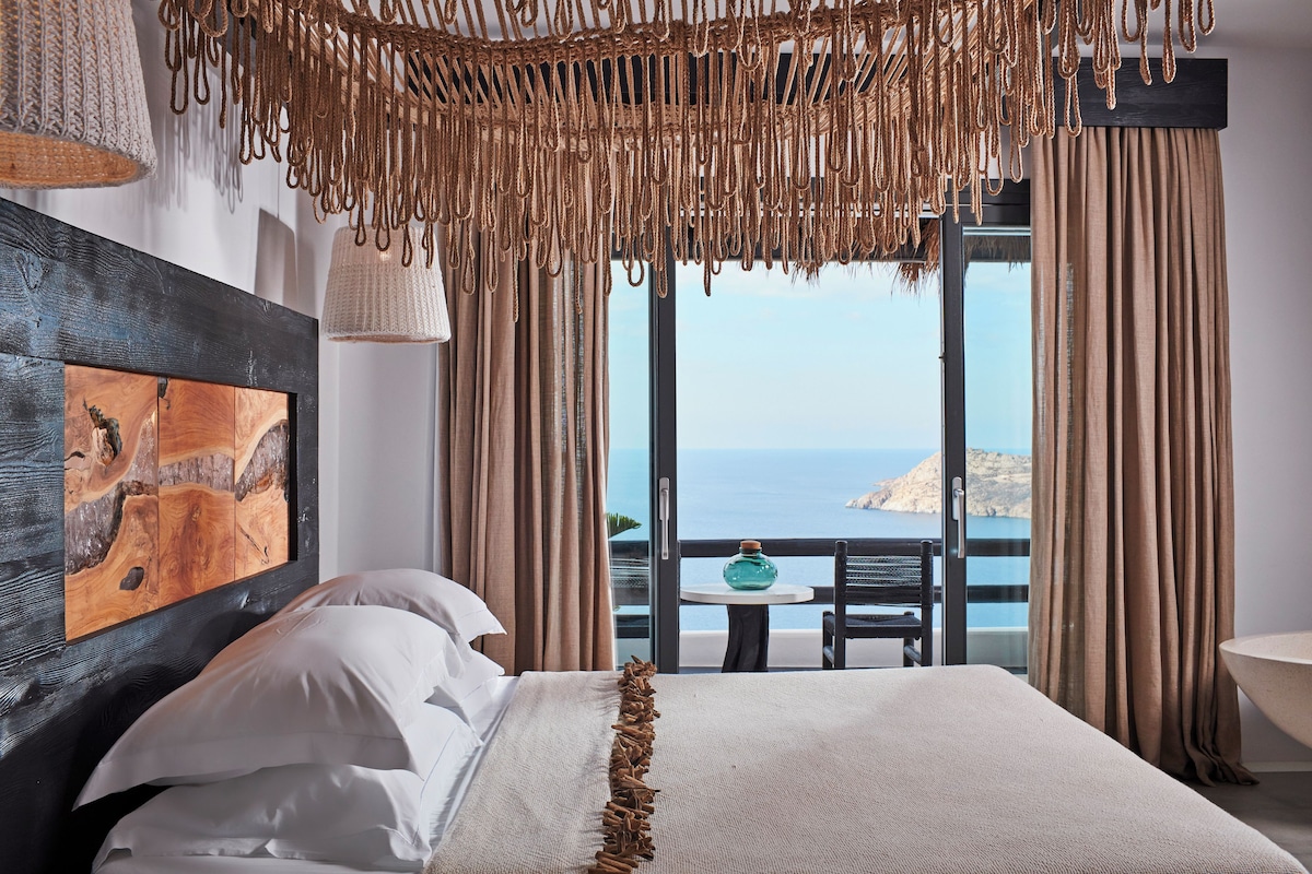 Un dormitorio con una cama grande, vista al mar y un cuadro en la pared.